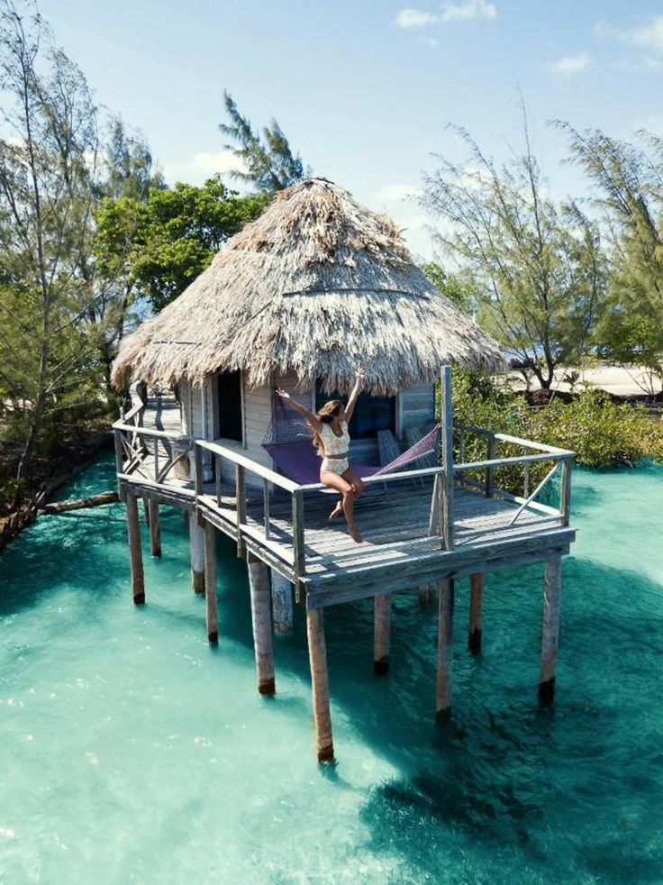 a woman standing on a dock in front of a hut