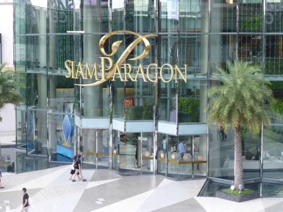 people walking in front of a large glass building with the name sam paragon on it