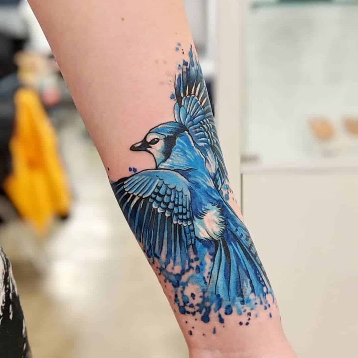 a blue bird tattoo on the arm