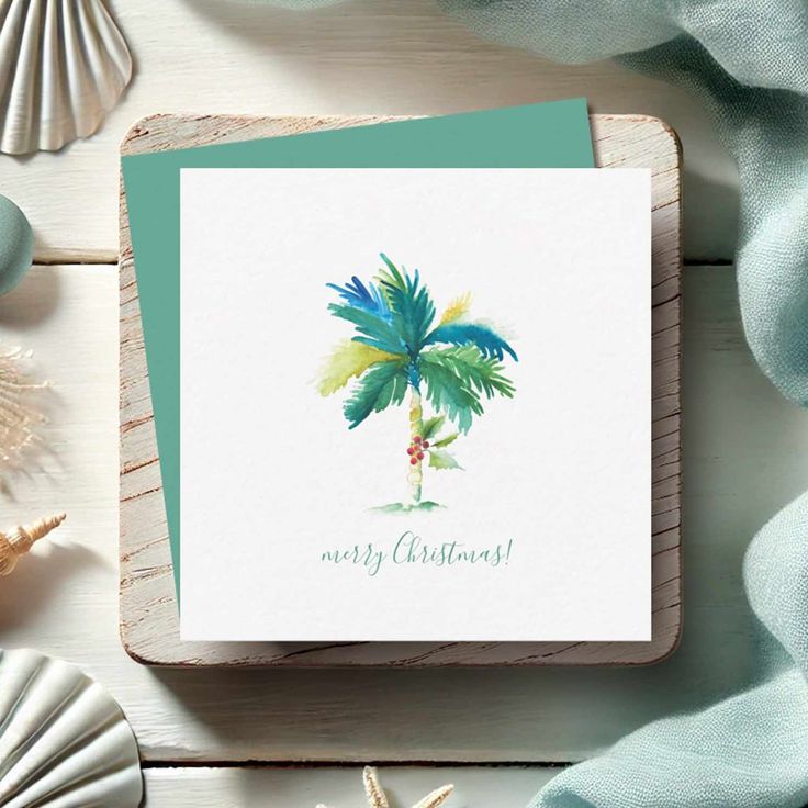 a card with a watercolor painting of a palm tree on it, surrounded by seashells