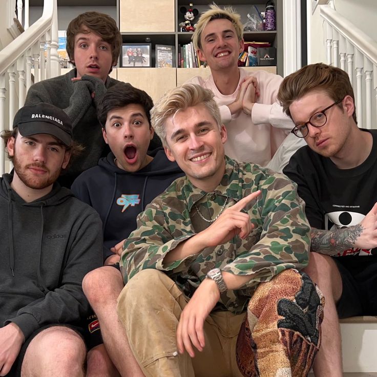 a group of young men sitting next to each other in front of a stair case