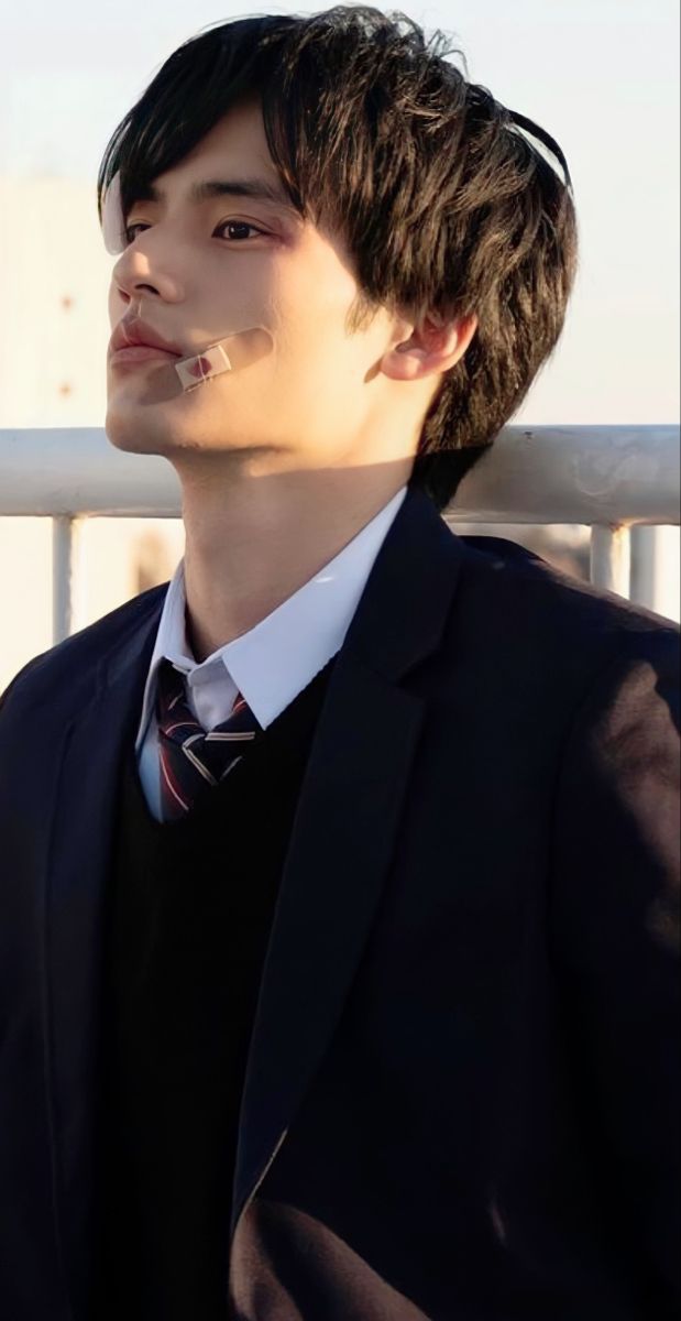 a young man wearing a suit and tie standing in front of a fence with his mouth open