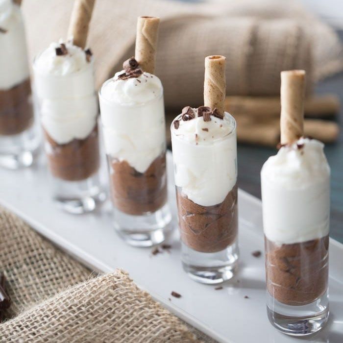 small desserts are lined up on a white tray with chocolate and marshmallows