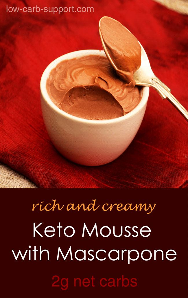 a white bowl filled with keto mousse next to a wooden spoon on top of a red cloth