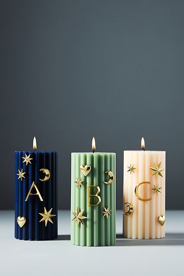 three candles with gold stars on them in different colors and shapes, one is blue, the other is green