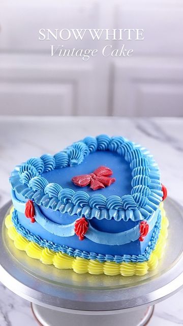 a heart shaped cake sitting on top of a white table next to a plate with red and blue frosting