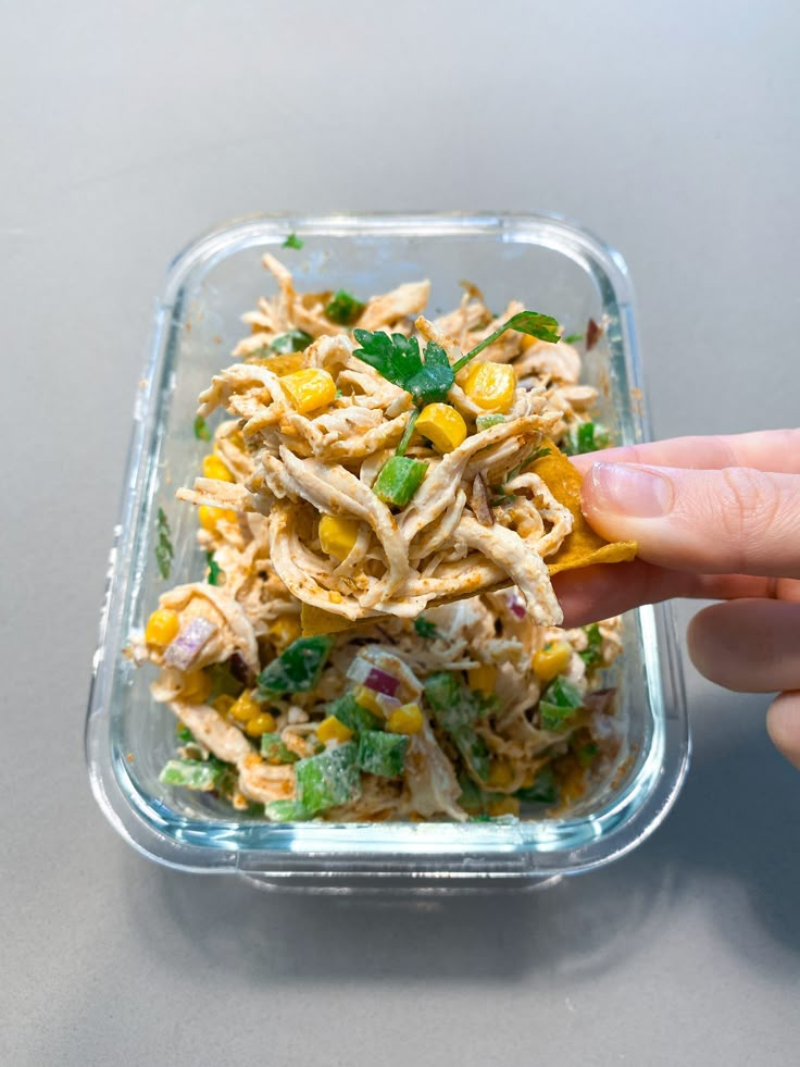 a person is picking up some food from a plastic container