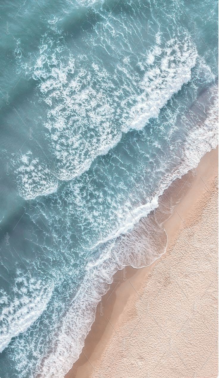 an aerial view of the ocean and beach with waves coming in from the shore, taken from above