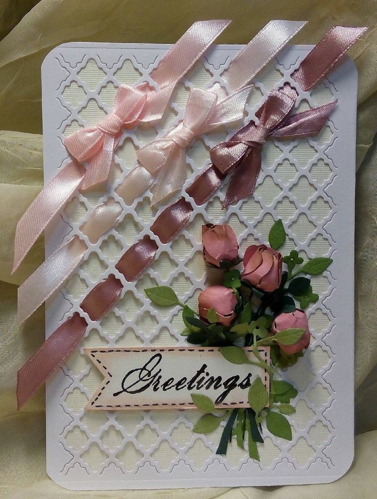 there is a card with roses and ribbons on the card, it says greetings