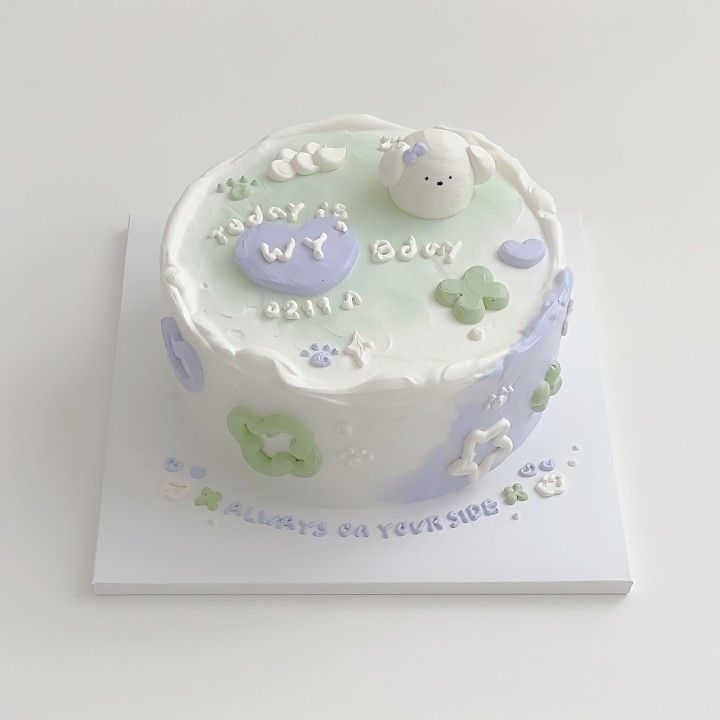 a white cake with blue and green frosting on it's top is sitting on a card