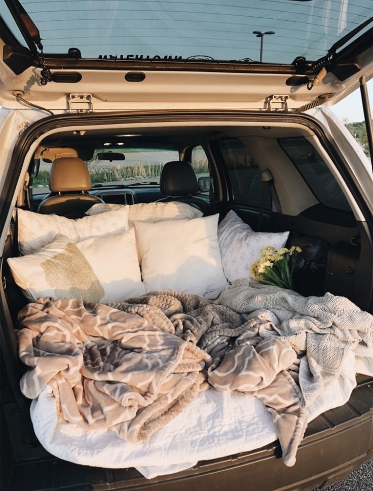 the back end of a car with blankets and pillows in it's trunk area