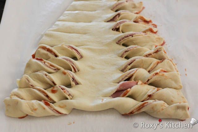 an uncooked pizza crust is sitting on a white tablecloth covered with red sauce