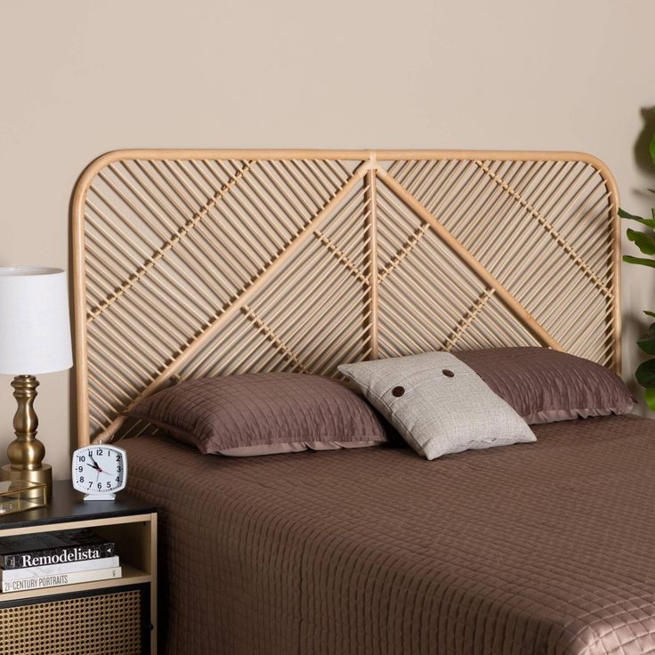 a bed with brown sheets and pillows next to a night stand, lamp and potted plant