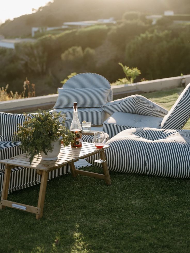 an outdoor seating area with striped cushions and a bottle of wine sitting on the table