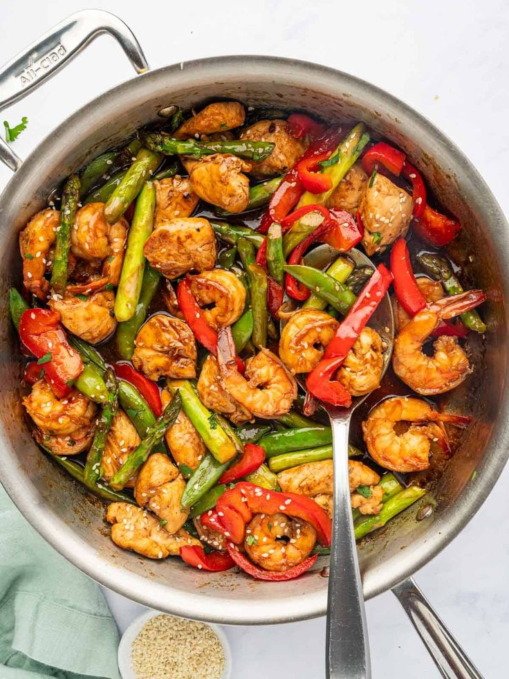 shrimp and vegetable stir fry in a pan with tongs