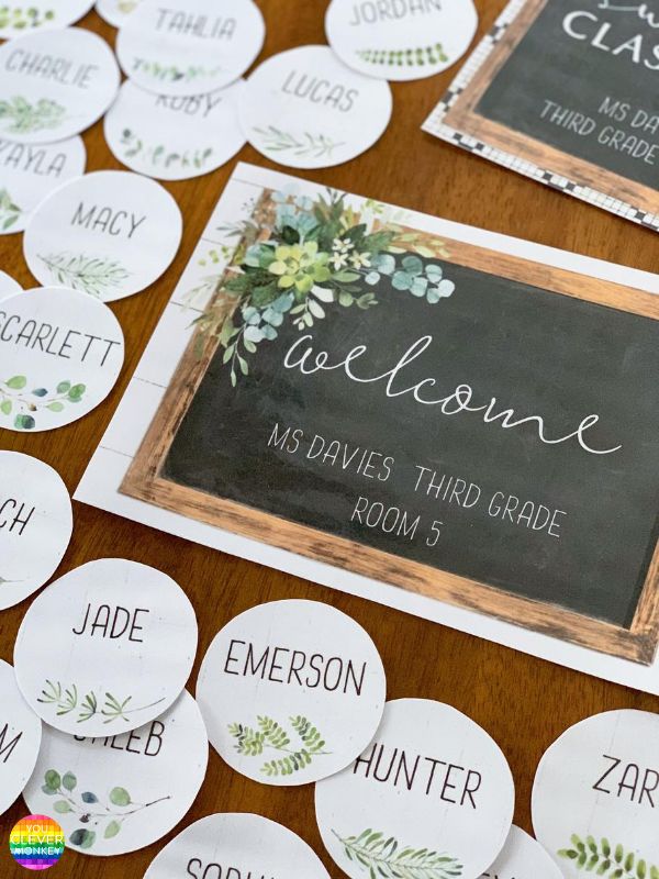 a wooden table topped with lots of white and green flowers next to a blackboard