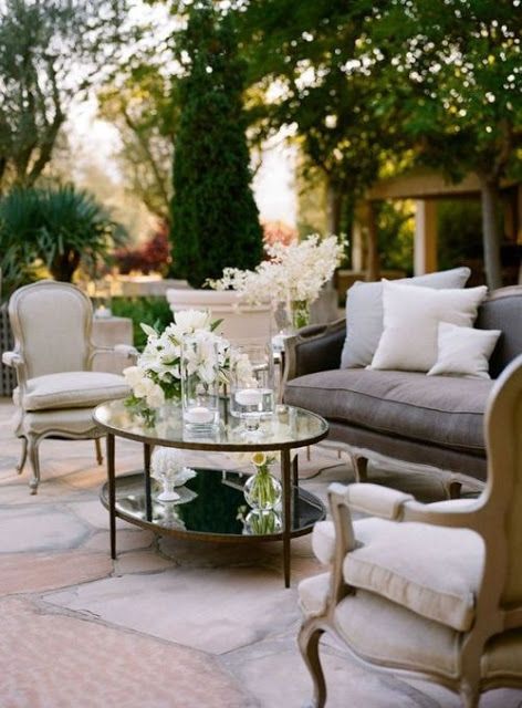 a living room filled with furniture and flowers on top of a glass topped coffee table