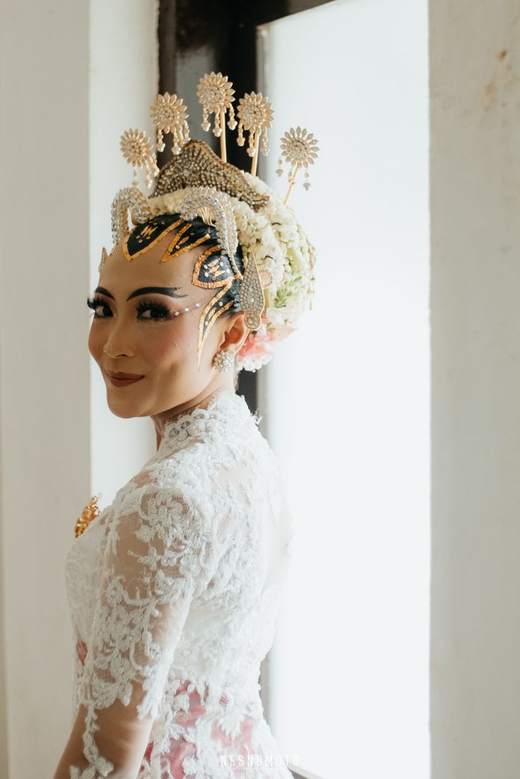 a woman in a white dress with flowers on her head and an elaborate tiara