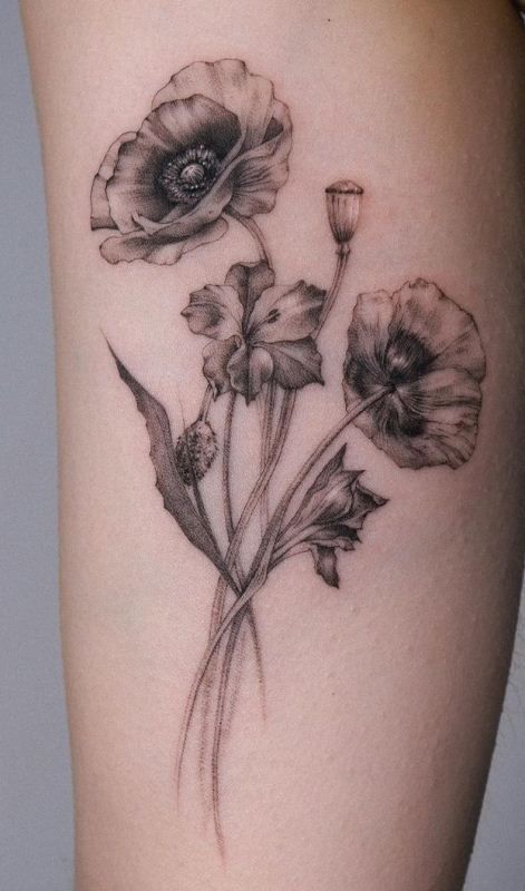 a black and white photo of flowers on the side of a woman's thigh