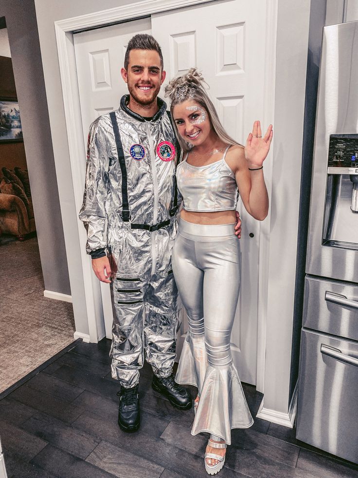 a man and woman dressed up as astronauts posing for a photo in front of a refrigerator