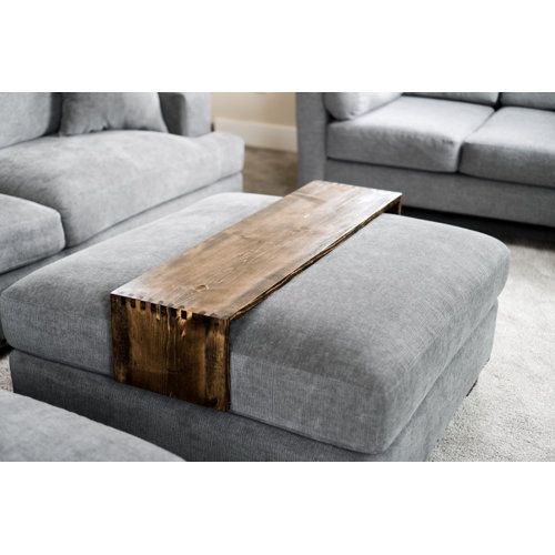 a wooden table sitting on top of a gray couch next to two grey sofas