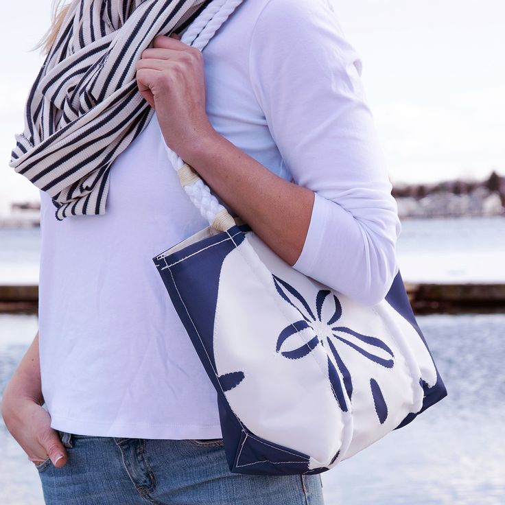 Sea Bags Recycled Sail Cloth White on Navy Sand Dollar Handbag - Here's an eco-friendly bag for nature lovers that's sure to bring back memories of great beach walks. The lucky sand dollar has deep symbolism for the spiritual among us, and it's also a standalone reminder of the many gifts of the sea. The sand dollar is printed on recycled sail cloth with our signature zig stitching around the edge. Hand-spliced white rope handles. Machine wash, line dry. Dimensions: 11" w x 11.5" h x 5.5" d. San Casual Travel Shoulder Bag Made Of Recycled Materials, Coastal Rectangular Bag For Daily Use, Coastal Style Rectangular Bag For Daily Use, White Coastal Rectangular Bag, White Coastal Bags For Everyday Use, Eco-friendly Beach Bag With Removable Pouch For Travel, Eco-friendly Beach Bag With Removable Pouch, Coastal Style Tote Bag For Daily Use, Coastal Style Natural Bag For Everyday Use