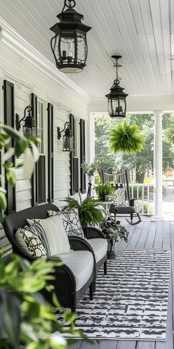 the front porch is decorated with black and white furniture, potted plants, and hanging lanterns