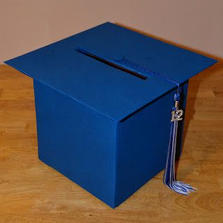 a blue box sitting on top of a wooden floor with a tassel hanging from it's side