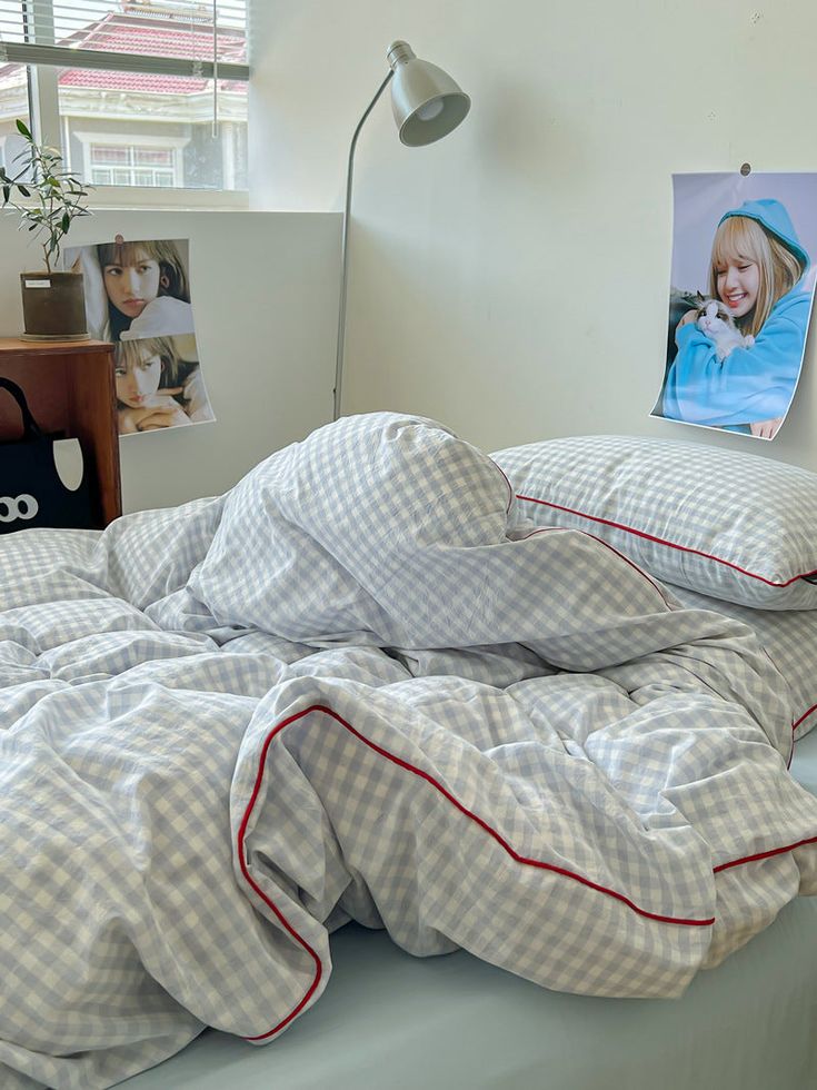 an unmade bed in a bedroom with pictures hanging on the wall and lamp next to it