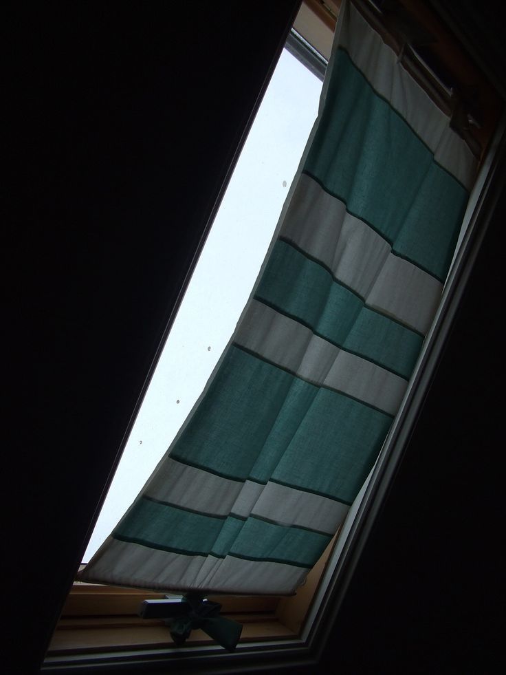 an open window with a green and white striped curtain hanging from it's side