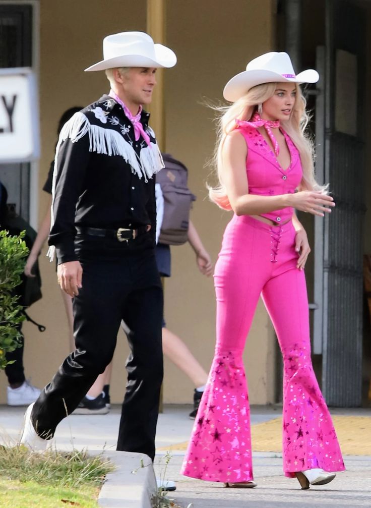 a man and woman in cowboy hats walking down the street