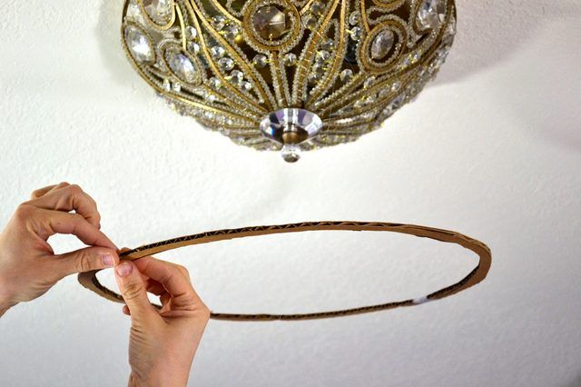 a person is holding a piece of string in front of a chandelier hanging from the ceiling