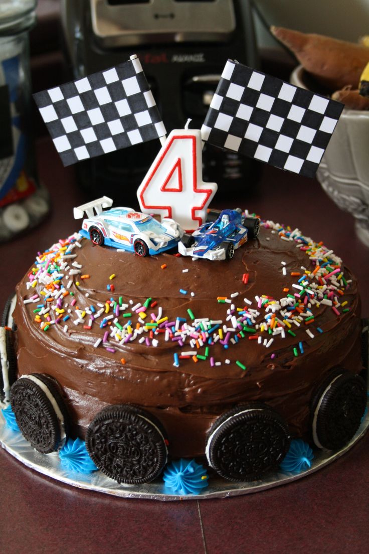 a birthday cake with cars on it and flags in the shape of number four sitting on a table