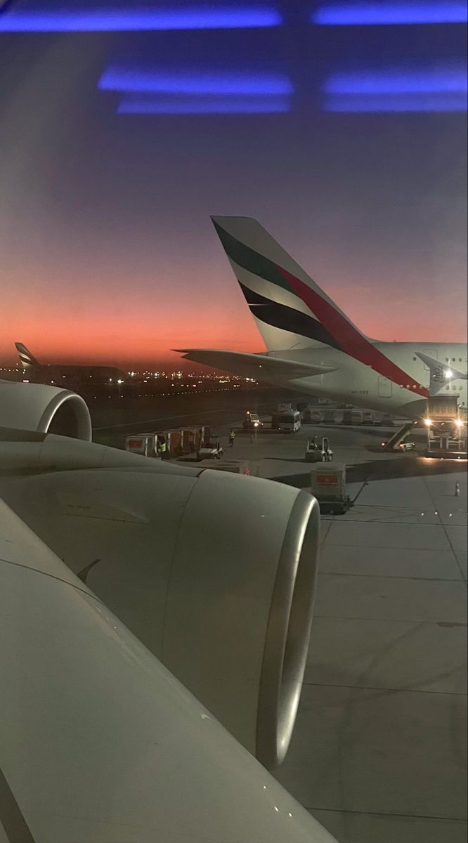 an airplane wing with the sun setting in the background