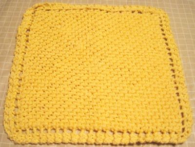 a yellow crocheted square sitting on top of a table