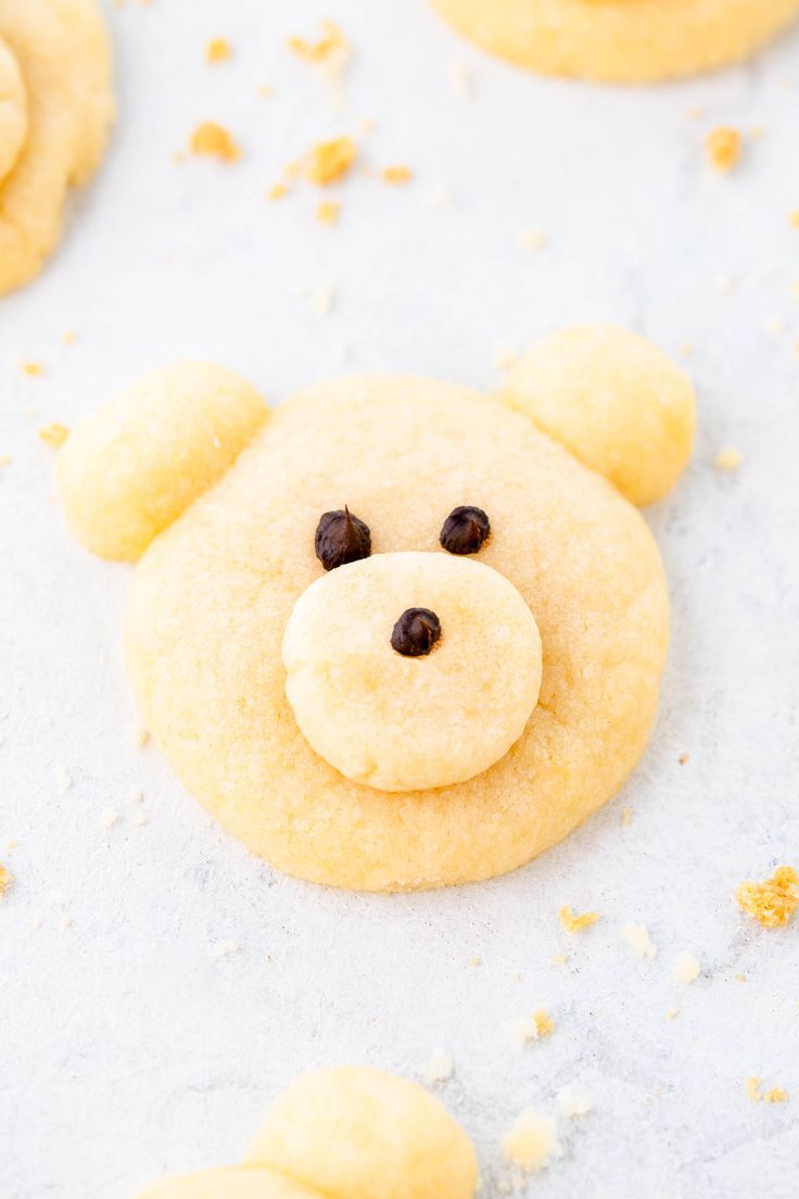 cookies shaped like a teddy bear with eyes and nose are arranged on a baking sheet