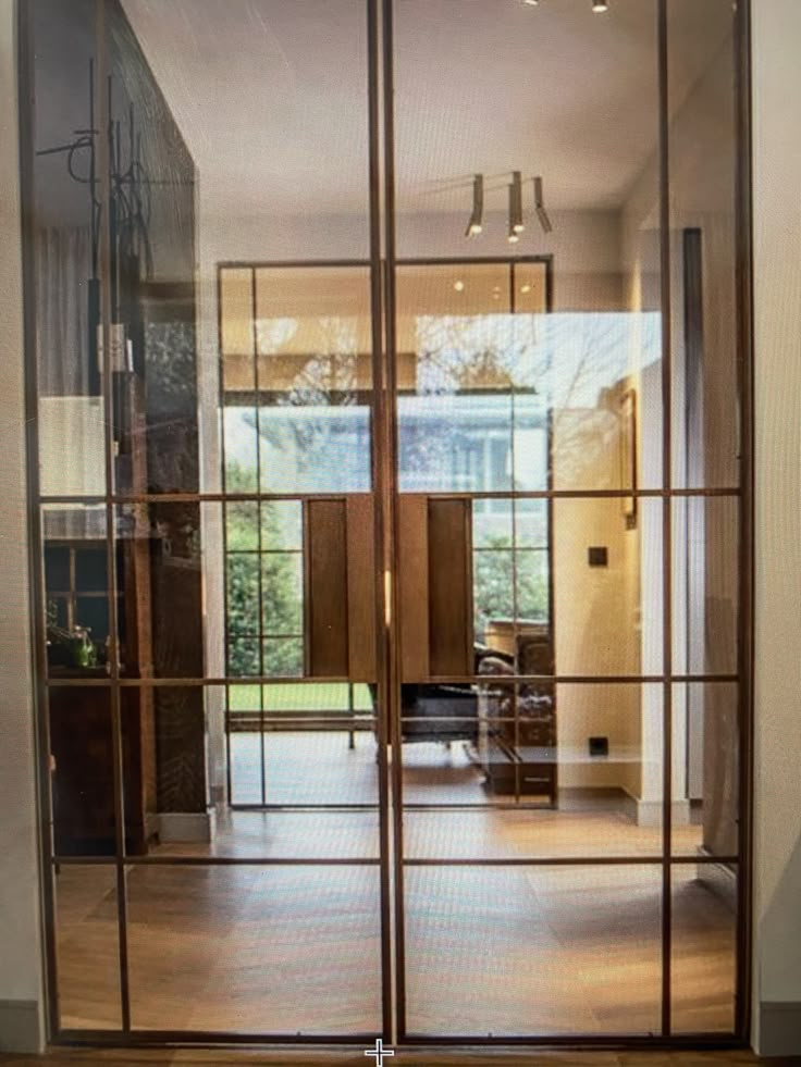 an open glass door leading to a living room with wood floors and furniture in the background