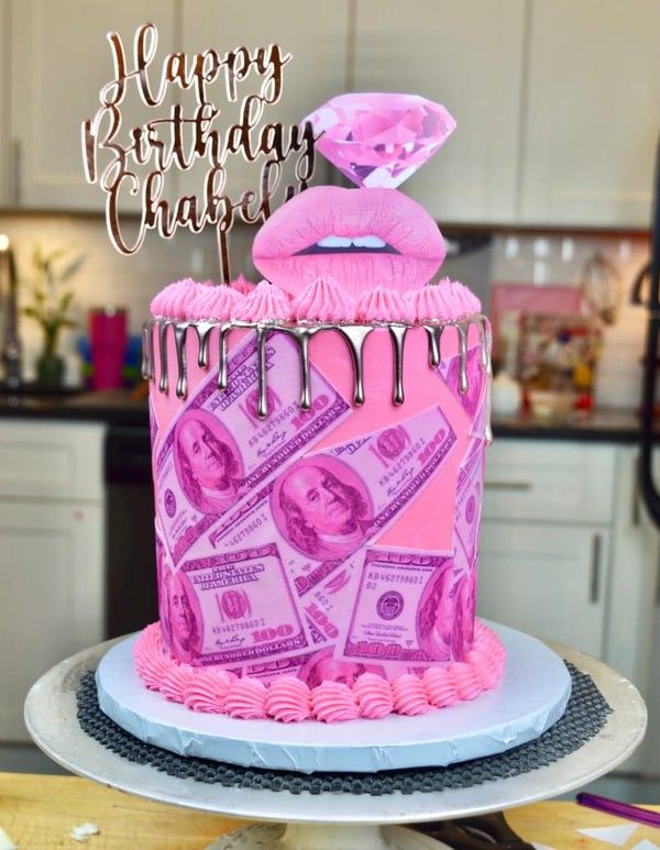 a pink birthday cake with money on top