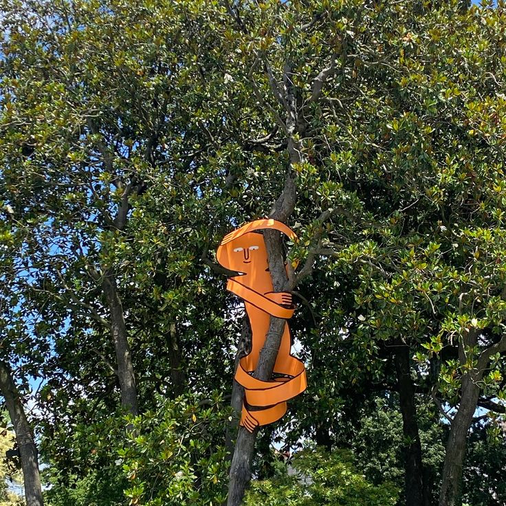 an orange parking meter in front of some trees