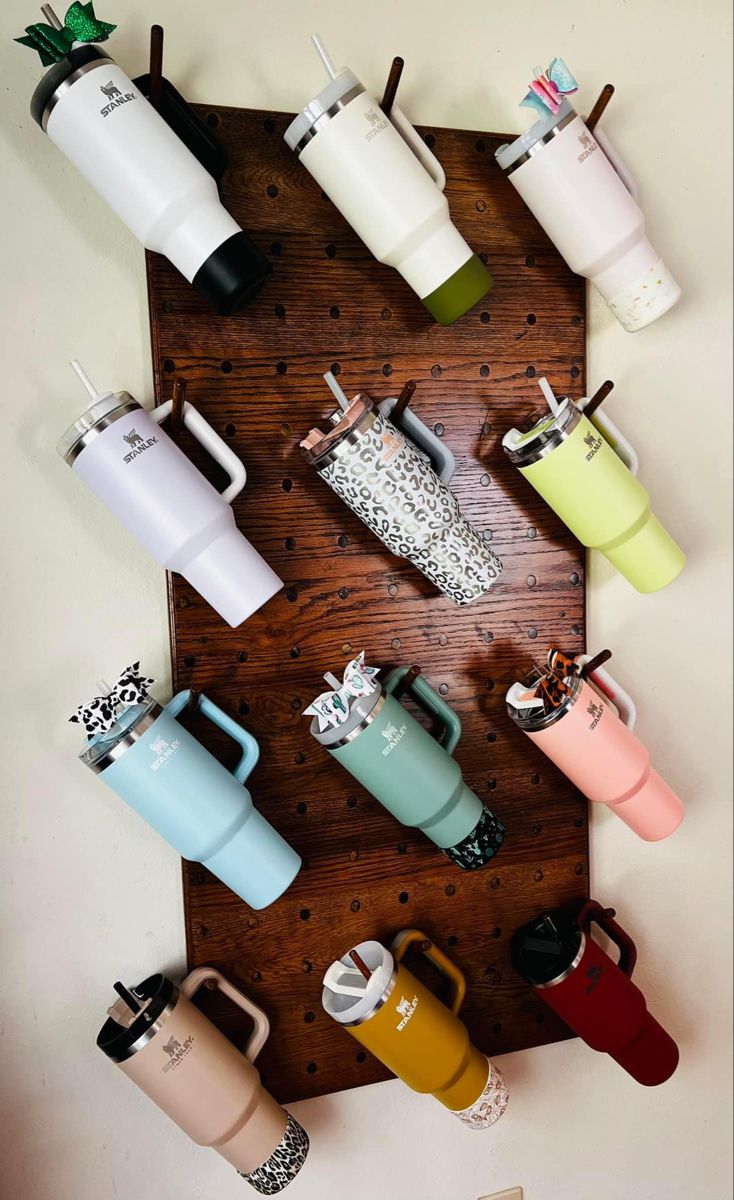 a wooden table topped with lots of different colored coffee mugs on top of it