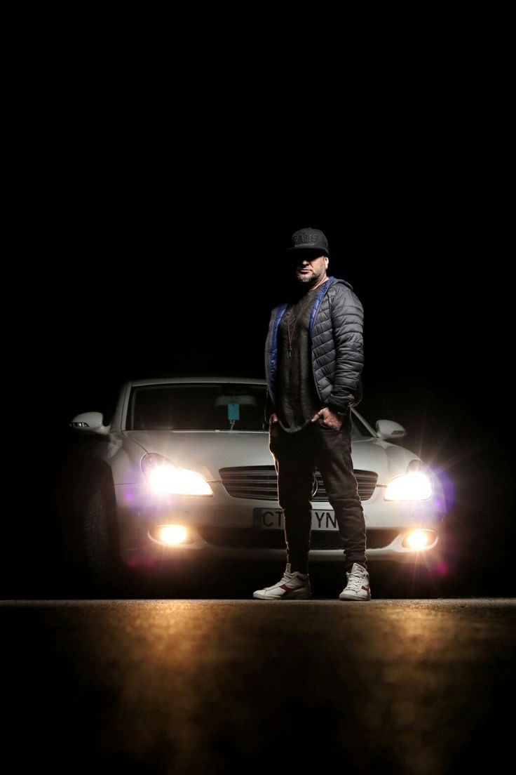 a man standing next to a car in the dark