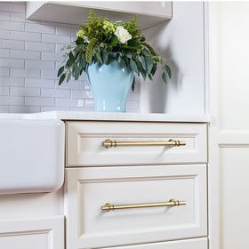 a blue vase with flowers on top of a white cabinet in a kitchen, next to a sink