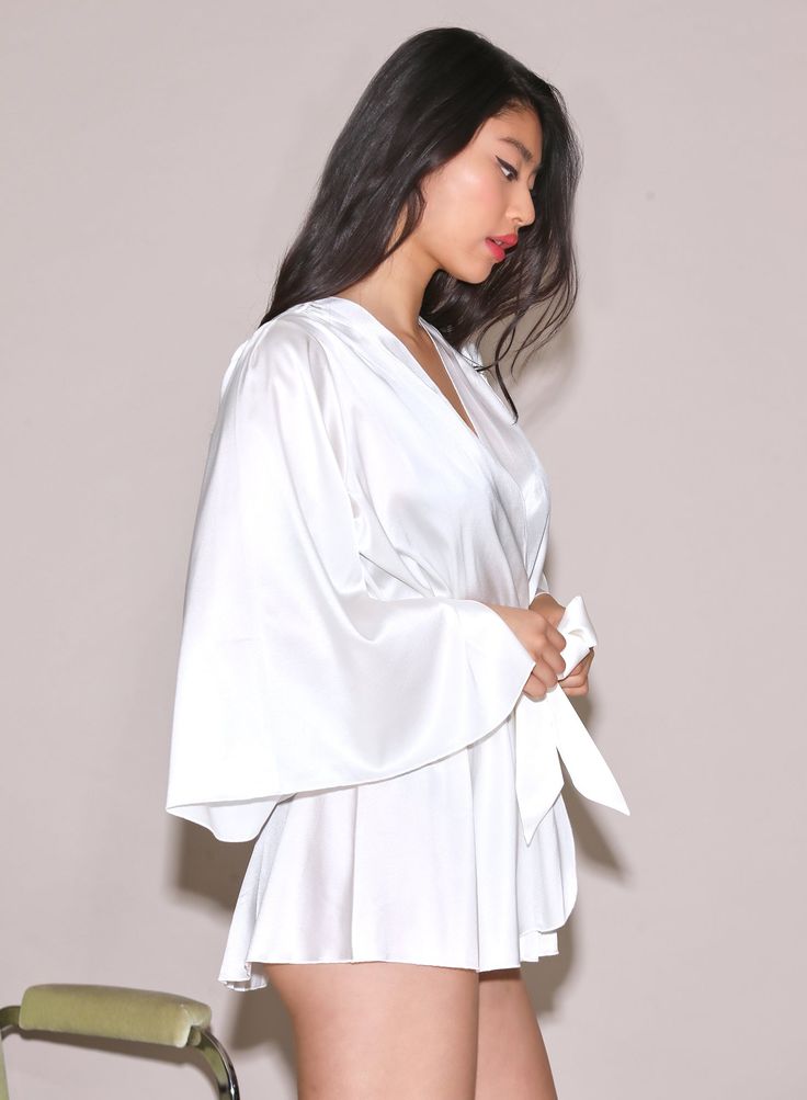 Our best selling Angel Sleeve Robe in luxe silk charmeuse. Features a playful fit with wide sleeves. Wraps across the body and is secured by a sash. Pair with the Gardenia Lace Demi Bra and Thong for an immaculate set. 92% Silk & 8% Spandex Dry clean only Model is 5'10 and wearing a size S/M. Chic Silk Sleepwear With Satin Finish, Satin V-neck Robe For Daywear, Spring Satin V-neck Robe, Elegant Satin V-neck Kimono, Silk V-neck Sleepwear For Evening, Chic Silk Sleepwear For Party, Chic Silk Long Sleeve Sleepwear, Chic Long Sleeve Silk Sleepwear, Silk Blouse For Loungewear