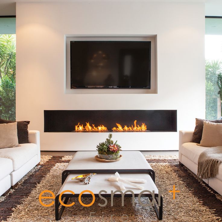 a living room with white couches and a flat screen tv mounted above the fireplace