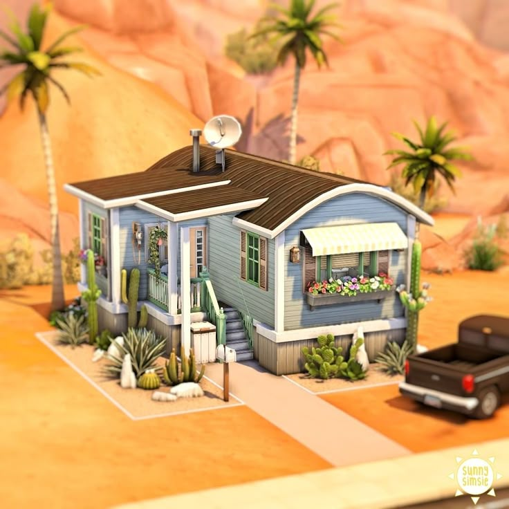 a small blue house sitting in the middle of a desert with palm trees and mountains behind it