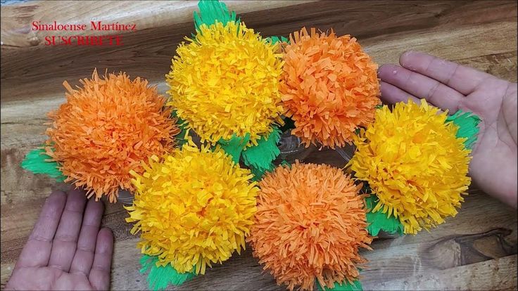 two hands are holding orange and yellow flowers