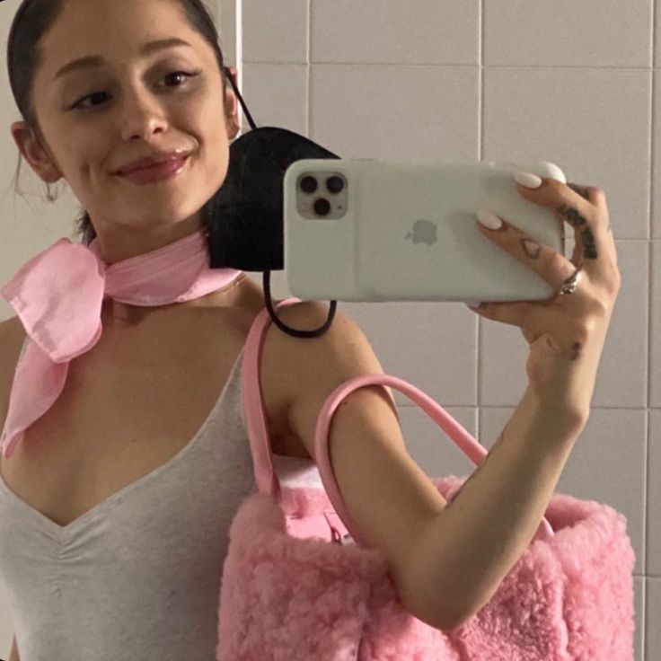 a woman taking a selfie in the mirror with her cell phone and pink handbag