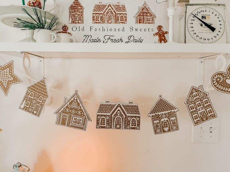 gingerbread cut out houses hanging on a string in front of a clock and other decorations