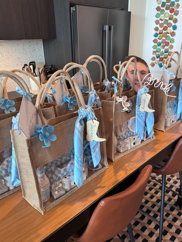 a woman is looking at bags with blue decorations on them sitting on a table in front of a refrigerator