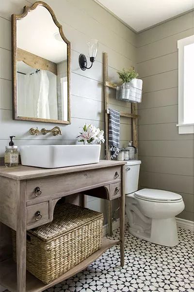 a white toilet sitting next to a sink in a bathroom under a wooden mirror mounted on a wall